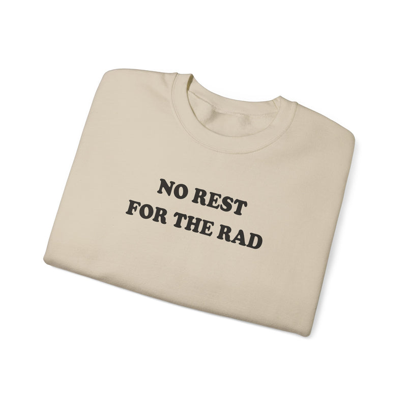 Folded sand colored cotton crewneck sweatshirt with black writing that says No Rest for the Rad.