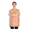Female model wearing peach colored T-shirt that says I am Muse Made.