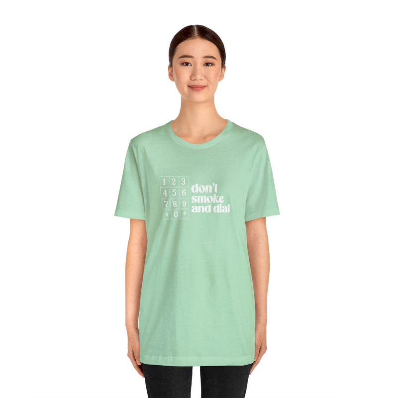 Model wearing a Green cotton Top Knot Goods t-shirt that says Don't smoke and Dial.