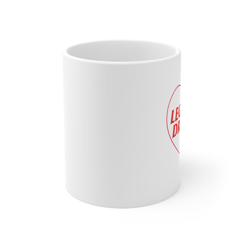 Side view of white ceramic coffee mug that has a red heart with Legalize Dreams written on it.