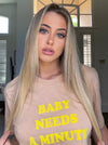 Top Knot Goods sand colored T-Shirt that says "Baby Needs a Minute."."