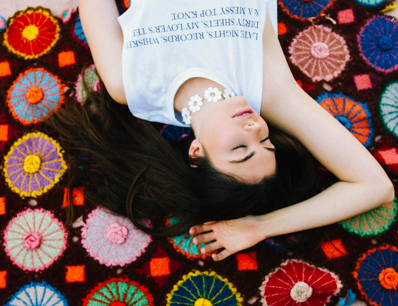 Girl laying on blankey wearing Top Knot Goods white cotton T-Shirt. 