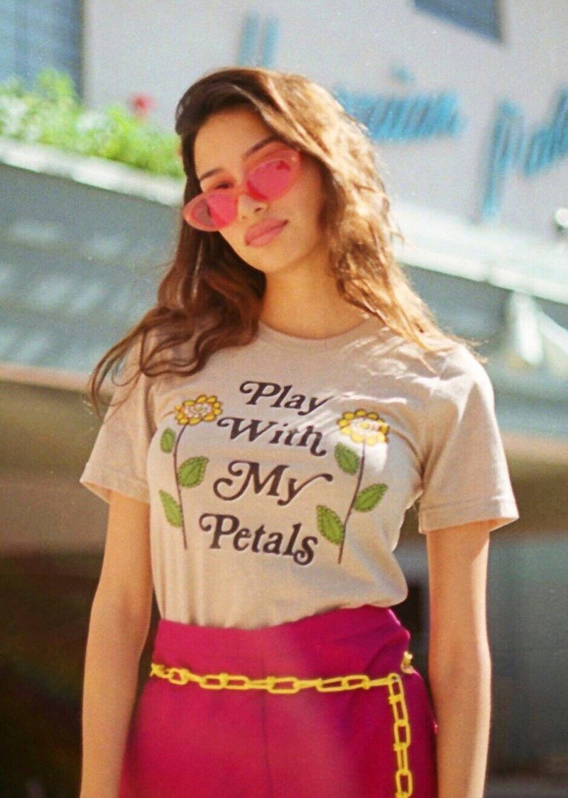Model wearing tan shirt with Play With My Petals with two flowers on the front.