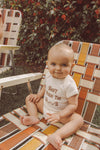 Cute baby sitting in a vintage chair wearing a funny baby onesie