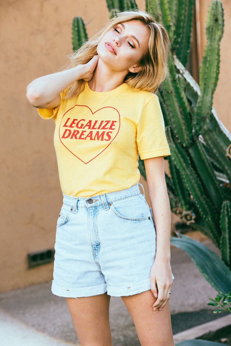Girl wearing yellow vintage inspired t shirt that says Legalize Dreams