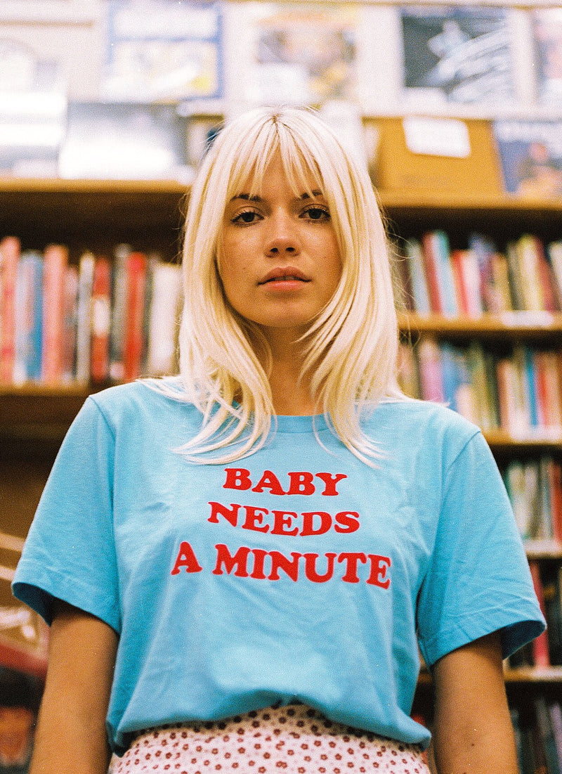 Girl in library wearing baby blue 1970s women's graphic t-shirt